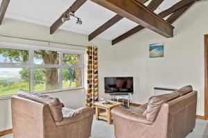 a living room with two leather chairs and a tv at Fuchsia Cottage in Saint Endellion