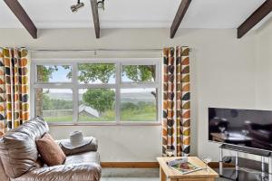 a living room with a couch and a large window at Fuchsia Cottage in Saint Endellion +9 photos