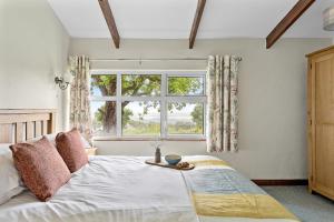 a bedroom with a large bed with a window at Fuchsia Cottage in Saint Endellion