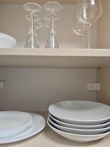 a stack of plates and wine glasses on a shelf at Emma's Appartment with Free Parking in Nivy +3 photos