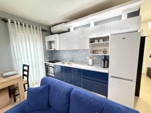 a kitchen with a blue couch and a white refrigerator at Riva'S Apartament in Shkodër