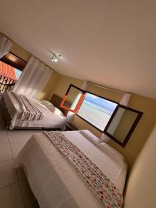two beds in a room with a large window at Pousada Dra Lindalva in Maragogi +25 photos