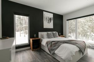 a bedroom with black walls and a bed and windows at Scenic Bright - Sauna - Fire - 20 min Tremblant in La Conception