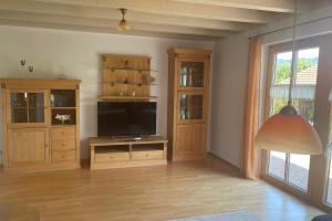 a living room with a flat screen tv and wooden cabinets at Ferienhaus Eugler in Weitnau