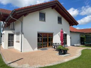 a white house with a patio and an umbrella at Ferienhaus Eugler in Weitnau