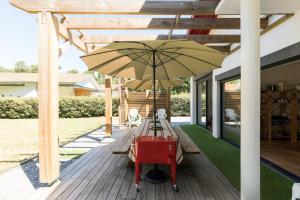 une terrasse en bois avec une table et un parasol dans l'établissement Havre de paix familial à Hossegor, à Soorts-Hossegor