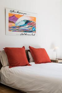 - un lit avec des oreillers rouges et un tableau mural dans l'établissement Havre de paix familial à Hossegor, à Soorts-Hossegor