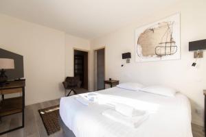 a white bedroom with a white bed and a chair at Villa Fabienne in city center with heated pool in Andernos-les-Bains