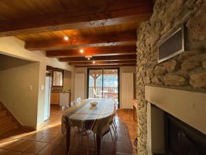 a dining room with a table and a stone fireplace at Les Buis in Belcastel
