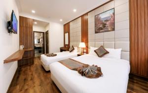 Una habitación de hotel con dos camas y un televisor. en Wisteria Hotel Dalat, en Da Lat 37 fotos más