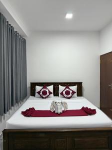 een slaapkamer met een groot bed met rode en witte kussens bij Dewliya Rest in Galle