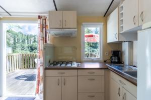 a kitchen with white cabinets and a view of a deck at Mobilhome Le Chataignier in Saint-Pompont