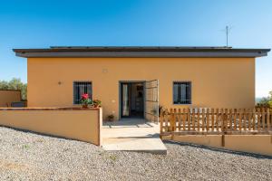 a small yellow house with a wooden fence at Affittacamere Gutturu e Forru in Villacidro
