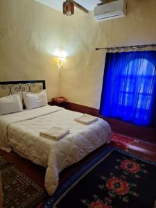 a bedroom with a large bed with a blue window at La Fibule D'or in Aït Benhaddou +71 photos