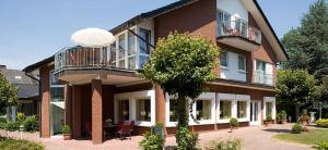 een groot bakstenen gebouw met een balkon en een boom bij Forellenhof in Bad Sassendorf