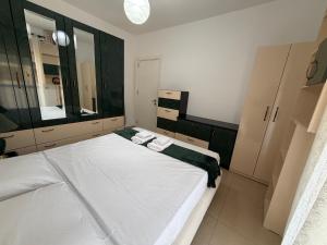 a bedroom with a large white bed and a mirror at Riva'S Apartament in Shkodër