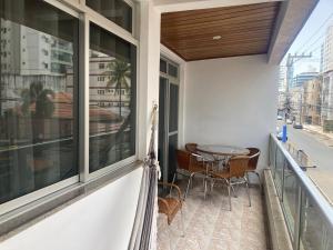a balcony with a table and chairs at Conforto e espaço - 3 quartos, 3 vagas e a 150m do mar in Guarapari