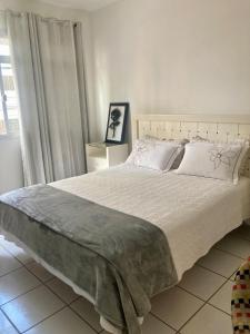 a bedroom with a large bed with white sheets and pillows at Conforto e espaço - 3 quartos, 3 vagas e a 150m do mar in Guarapari