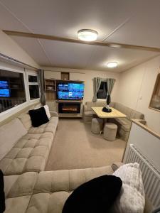 ein großes Wohnzimmer mit einem Sofa und einem TV in der Unterkunft Summer Breeze Deluxe in Skegness