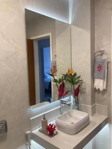 a bathroom with a sink and a mirror at Conforto e espaço - 3 quartos, 3 vagas e a 150m do mar in Guarapari +61 photos