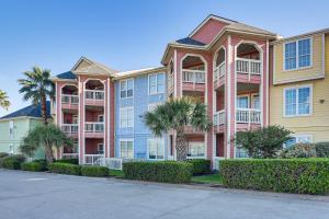 ガルベストンにあるPool Access and Balcony Beachfront Galveston Condo!のヤシの木と茂みのある大きなアパートメントビル