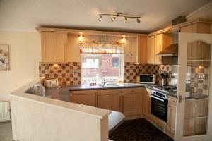 Una cocina grande con gabinetes de madera y fregadero. en Saffron Lodge With Hot Tub, en Malton