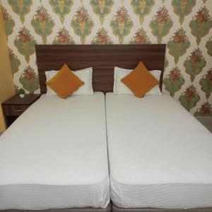 1 dormitorio con 2 camas con almohadas blancas y naranjas en The Royals Home Stay, en Deoghar