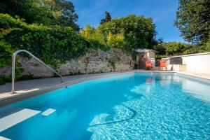a swimming pool with blue water in front of a stone wall at Gîte des Fours à Chaux in Saumur