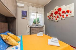 Un dormitorio con una cama amarilla con flores rojas en la pared en Casa Musa Giardini Naxos, en Giardini Naxos