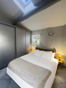 Un dormitorio con una gran cama blanca con tragaluz. en Le Soleillant Havre De Paix, en LʼIsle-sur-la-Sorgue