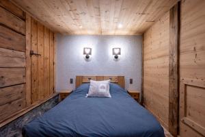 ein Schlafzimmer mit einem blauen Bett in einem Holzzimmer in der Unterkunft Le Logis in La Giettaz