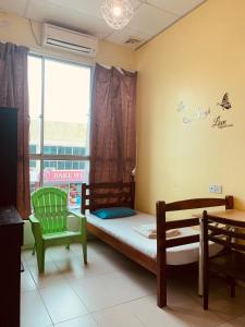 a bedroom with a bed and a chair and a window at Prima B&B Hostel in Sandakan