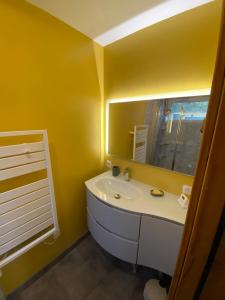 un bagno giallo con un lavandino e uno specchio di studio classé à sommières a Sommières