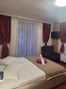 una camera da letto con un grande letto bianco e una sedia di Pensiunea ELEMAR ad Azuga