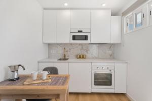 コスタ・デル・シレンチオにあるA T Suite Costa del Silencioの白いキャビネットと木製のテーブルのあるキッチン