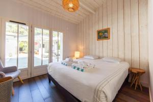 a bedroom with a large white bed and a window at Villa Du Phare avec piscine chauffée pour 14 perso in Cap-Ferret