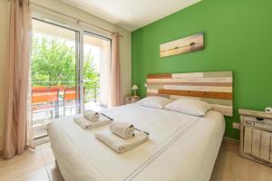 a bedroom with a large white bed with a green wall at Appartement Villa De L'Arche en plein centre-ville in Andernos-les-Bains