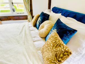 a white bed with blue pillows on it at Log- burner, dog friendly- woodland views with walking trails and local pub on your doorstep! Popular walking trails nearby-Malvern Hills and the Brockhampton Estate- Peaceful village on the border of Hereford and Worcester in Worcester