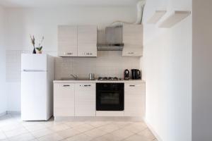 Una cocina con gabinetes blancos y un refrigerador blanco. en De Homes - Appartamento con Terrazza vicino Assago e Milano, en Buccinasco