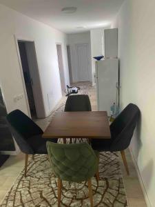 a dining room with a wooden table and green chairs at Villa Ola in Gjilan +8 photos