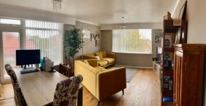 サウスポートにあるSouthport-Birkdale Luxury Havenのリビングルーム(黄色のソファ、テレビ付)