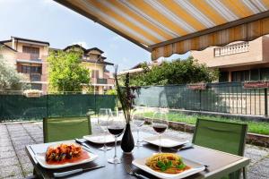 Una mesa con dos platos de comida y copas de vino. en De Homes - Appartamento con Terrazza vicino Assago e Milano, en Buccinasco