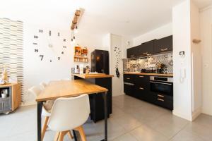 a kitchen with black cabinets and a wooden table at Appartment Christine in Lège city for 5 persons in Lège-Cap-Ferret