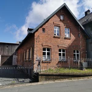 a red brick building with a fence in front of it at Alte Schlosserei in Presseck