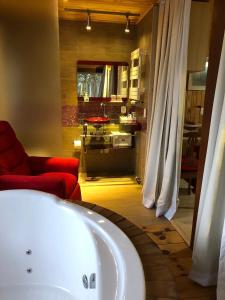 a bathroom with a bath tub and a red couch at A Cabanha in Caçador