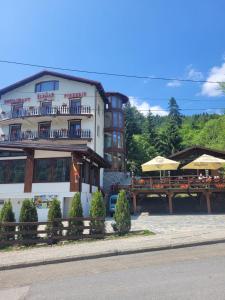 un hotel con tavoli e ombrelloni di fronte di Pensiunea ELEMAR ad Azuga