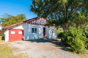 een huis met een rode deur en een boom bij Cozy Landes House in Soorts-Hossegor