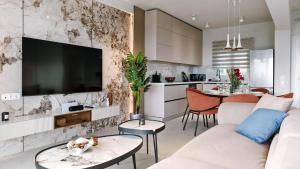 ein Wohnzimmer mit einem weißen Sofa und einem Fernseher in der Unterkunft Mira Mare Luxury Villa by Aktis Villas in Nea Skioni