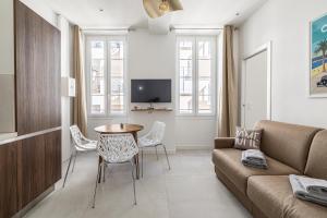 ein Wohnzimmer mit einer Couch und einem Tisch und Stühlen in der Unterkunft Cannes City Suites - 4 appartements neufs au coeur de Cannes in Cannes