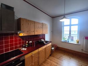 a kitchen with wooden cabinets and a red tiled wall at Zwei "Giebelwohnungen" im Kunstgut Krahne in Krahne